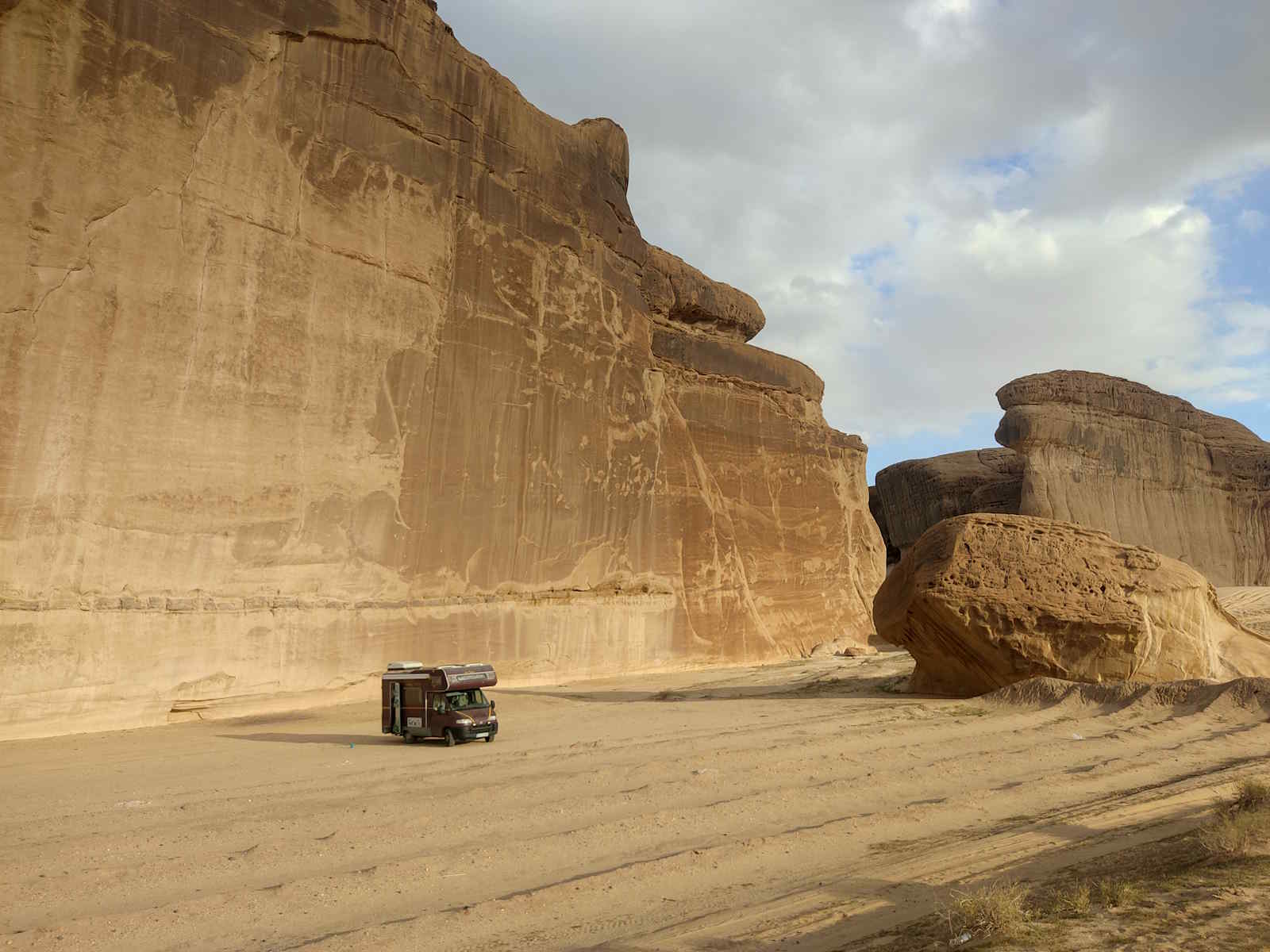 Wohnmobil vor einer Felswand in der Wüste von Saudi-Arabien